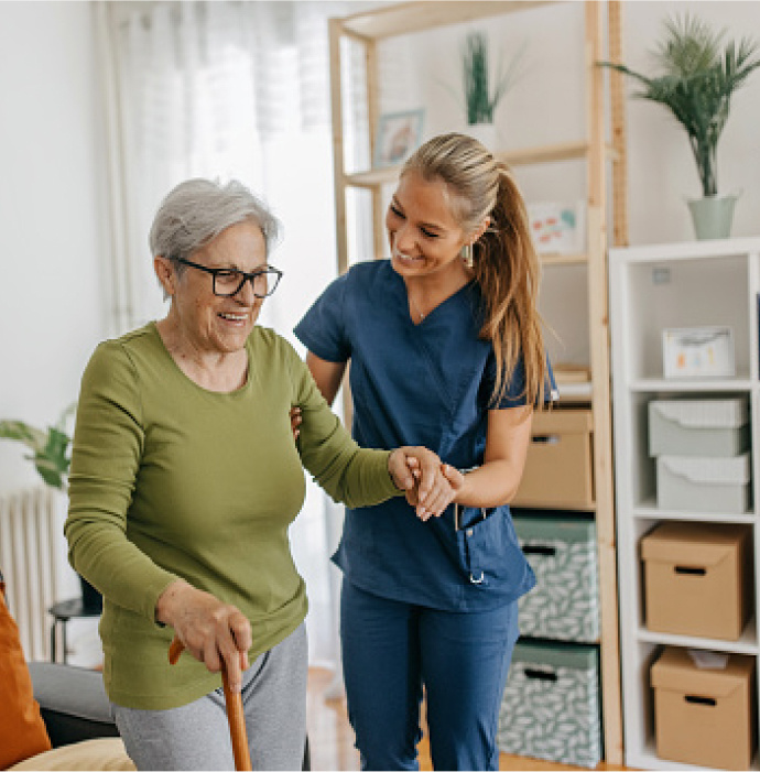 Aid helps a woman walk across the room. 