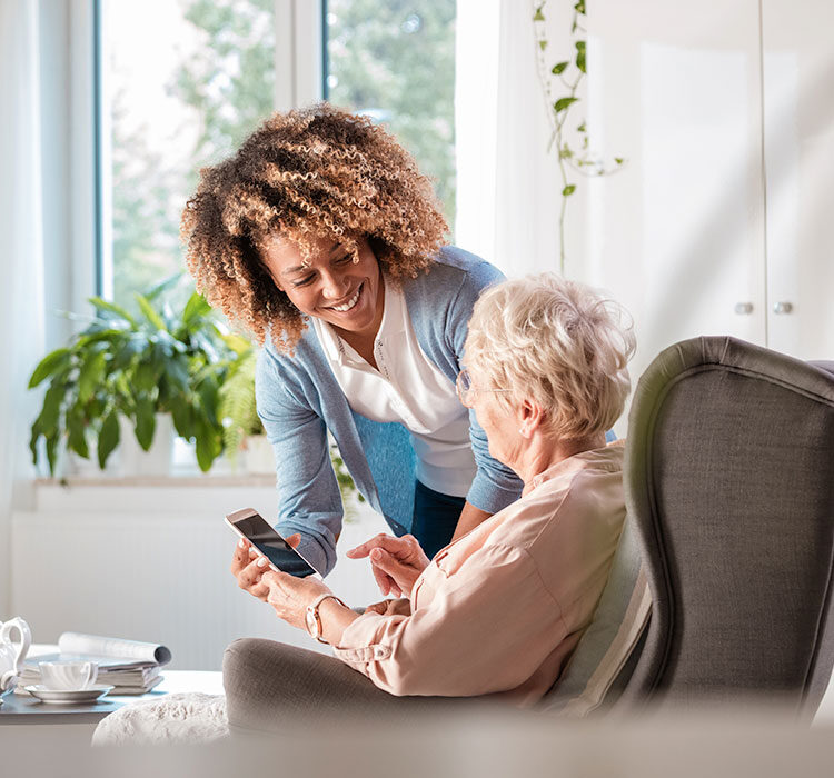 Volunteer helps an older woman with her phone. 